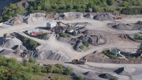 quarry - heavy machinery, dump trucks, and crusher at open-pit mine. - aerial shot