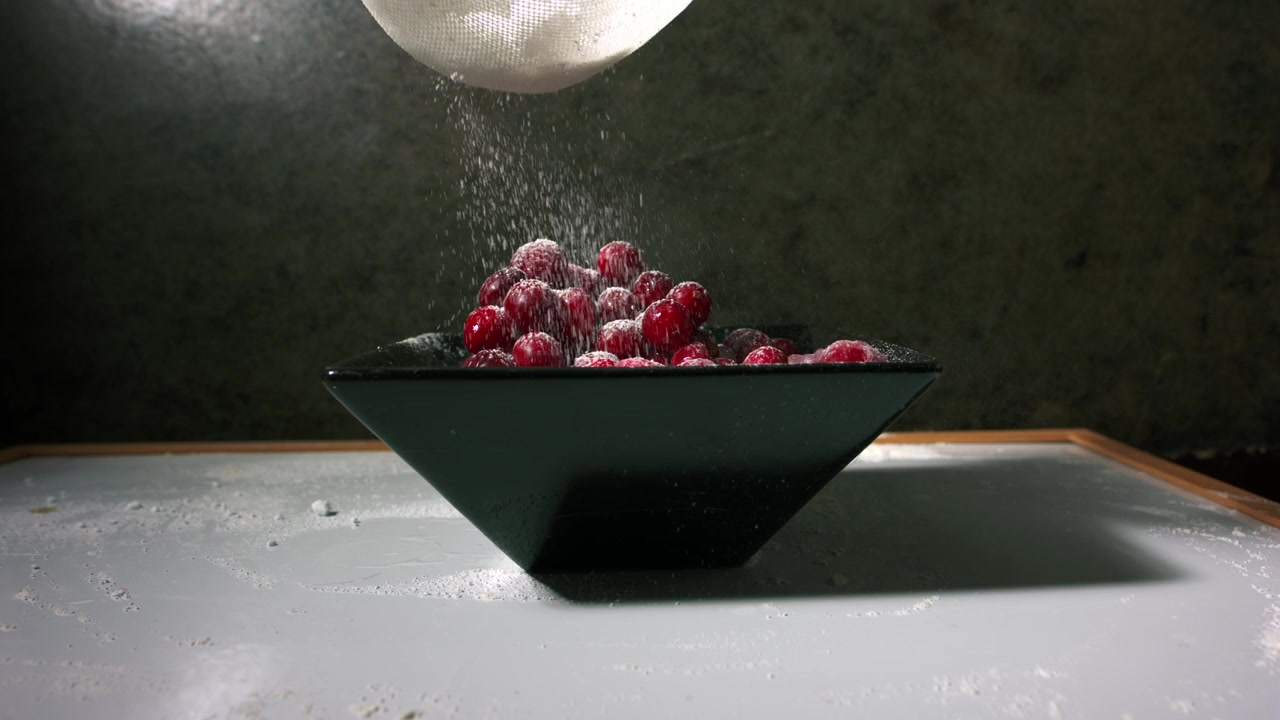 Sprinkling sugar on frozen bowl of cranberries 4k close up slow motion shot