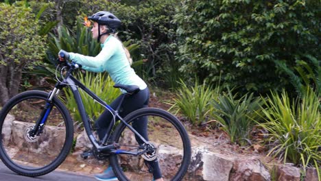 Female-cyclist-walking-with-mountain-bike-in-forest