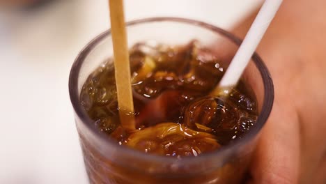 hand stirring iced tea with straw and stick