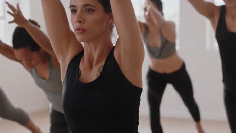 Hermosa-Mujer-Hispana-De-Yoga-Practicando-Meditación-En-Pose-Guerrera-Con-Un-Grupo-De-Mujeres-Multirraciales-Disfrutando-De-Un-Estilo-De-Vida-Saludable-Haciendo-Ejercicio-En-Un-Gimnasio