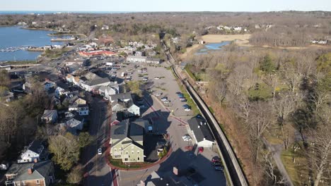 aerial push forward parallel with railroad tracks and a small, downtown street in a coastal new england town