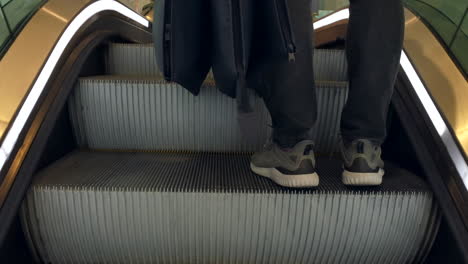 man with shopping bags riding the escalator in a shopping mall