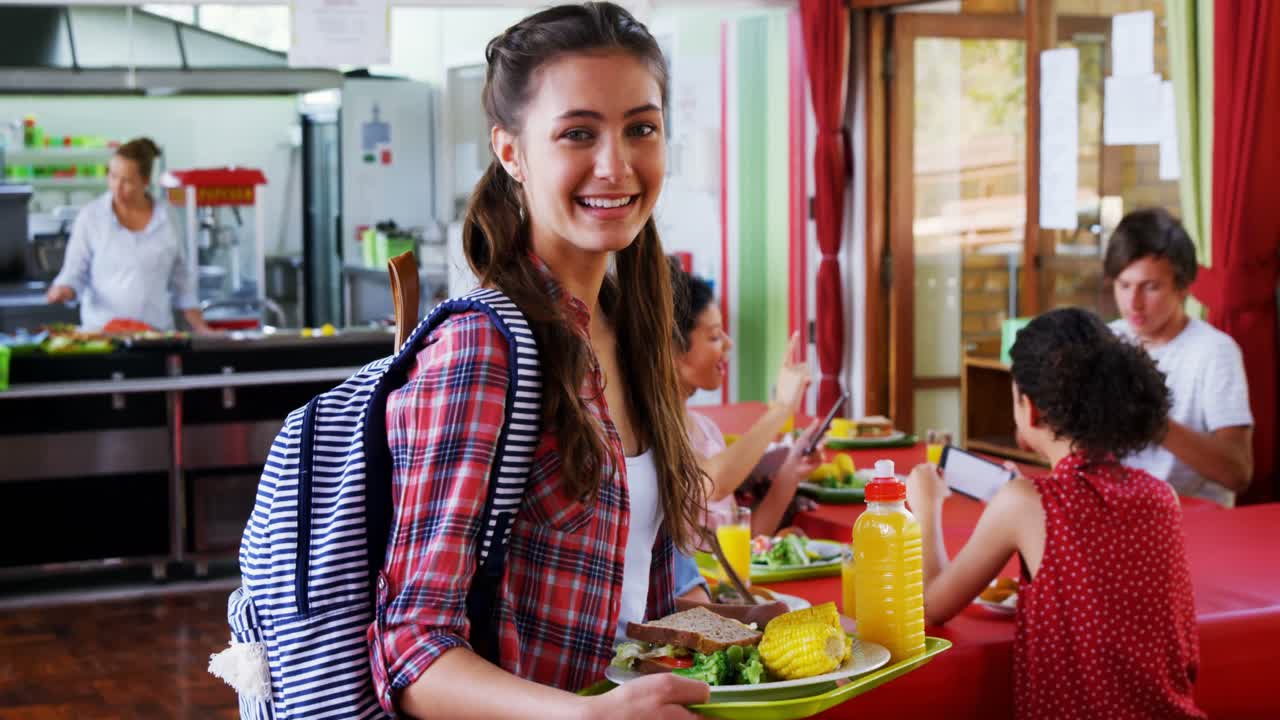 retrato de una estudiante feliz sosteniendo el desayuno en un plato
