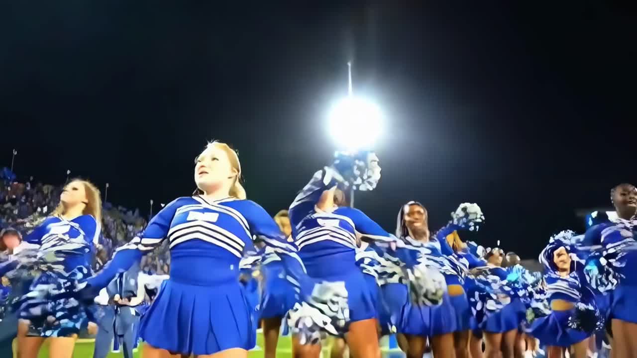 Dynamisk video af cheerleadere i blå uniformer, optaget fra en lav engel om natten