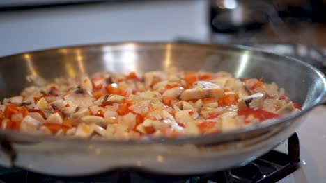 mezcla vegetariana de pimientos rojos picados, cebollas y champiñones en una sartén humeante - cámara lenta