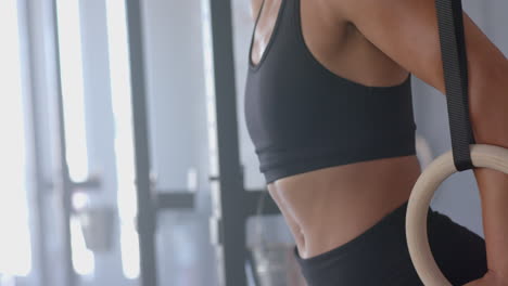exercising on gymnastic rings, strong fit woman in sportswear training upper body, copy space