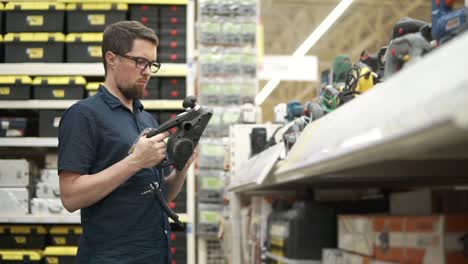 man examining an electric sander in a hardware store