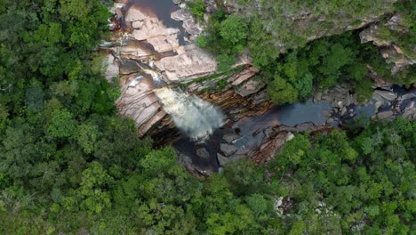 Aerial-drone-rising-top-down-wide-shot-of-the-incredible-Mosquito-Falls-surrounded-by-tropical-jungle-and-cliffs-in-the-Chapada-Diamantina-National-Park-in-Northeastern-Brazil-on-a-sunny-summer-day