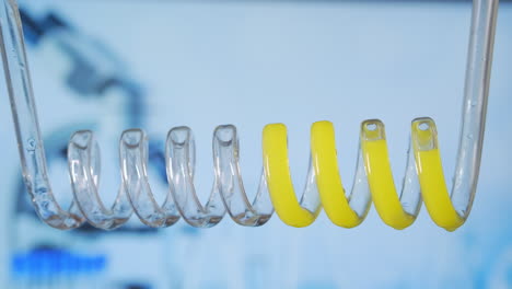 movimiento cercano y lento de líquido amarillo en espiral horizontalmente de derecha a izquierda en un condensador de vidrio científico. desarrollo y búsqueda de una vacuna. investigación química de coronavirus. pruebas de medicamentos. imágenes de alta calidad 4k