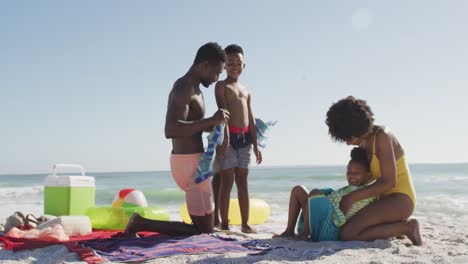 Lächelnde-Afroamerikanische-Eltern,-Die-Ihre-Kinder-Am-Sonnigen-Strand-Abtrocknen