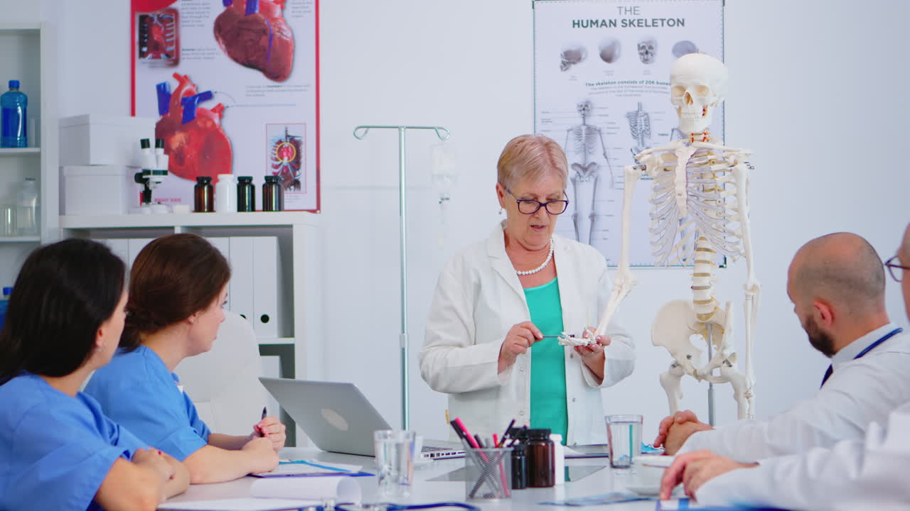 Elderly woman doctor showing the work of human's hand on skeleton model