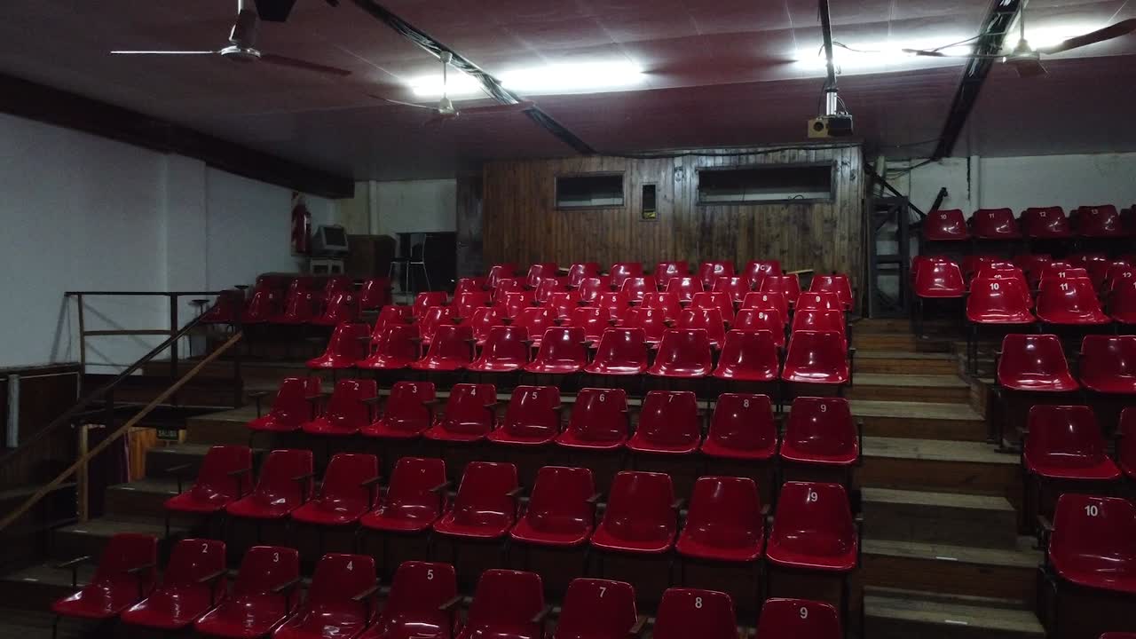 sala de teatro vacía, gradas rojas sin espectadores