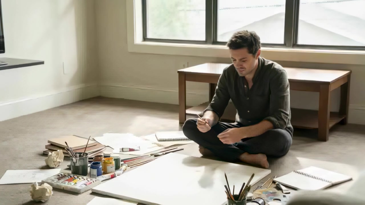 Rotating pen, male wearing dark shirt preparing to paint on floor near window with blank canvas