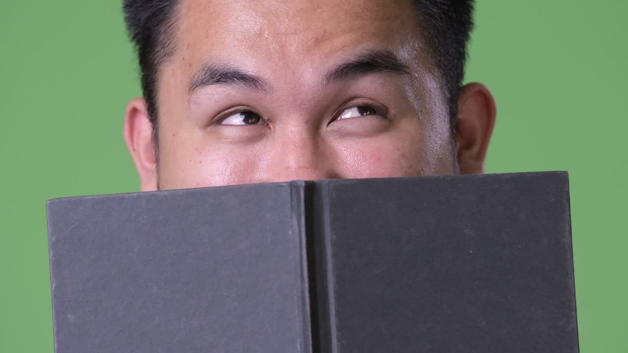 초록색 배경에 젊은 잘생긴 과체중 아시아인