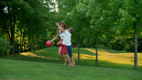 mother and children playing with ball in meadow. family enjoying time outside