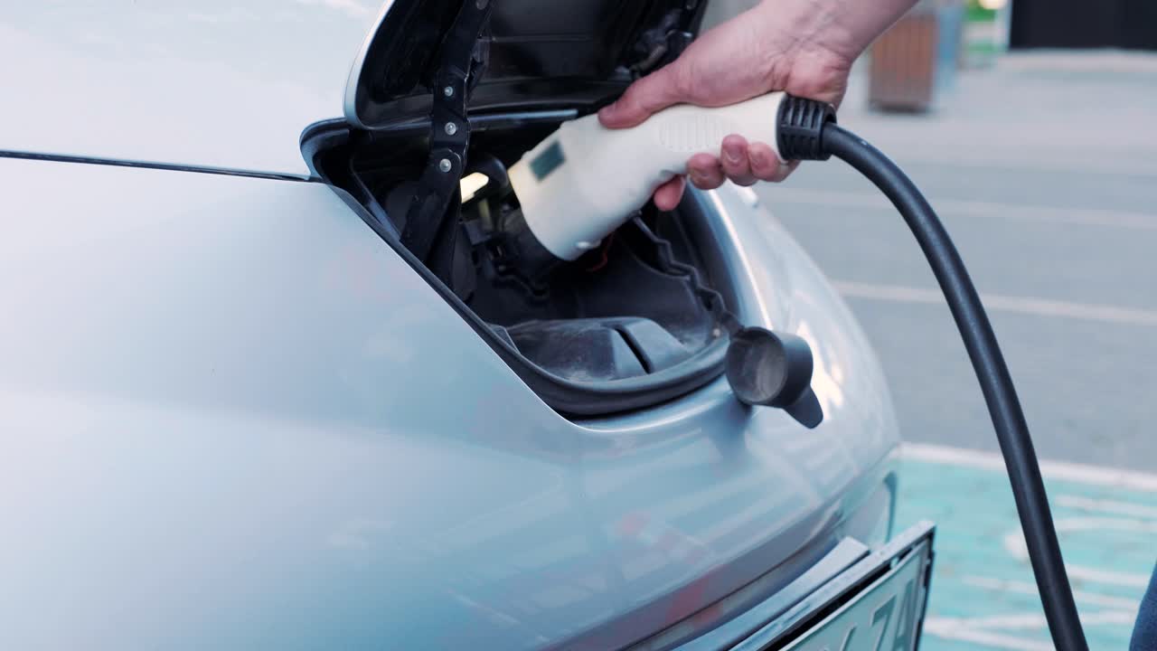 Bir elektrikli arabanın yakıt ikmal işlemi. Elektrikli eco arabanın şarj olduğu kapağın altından bir çekim. Elektrikli araba şarj kapağı otomatik olarak açılıyor. Bir erkek eli bir elektrikli araba takıyor