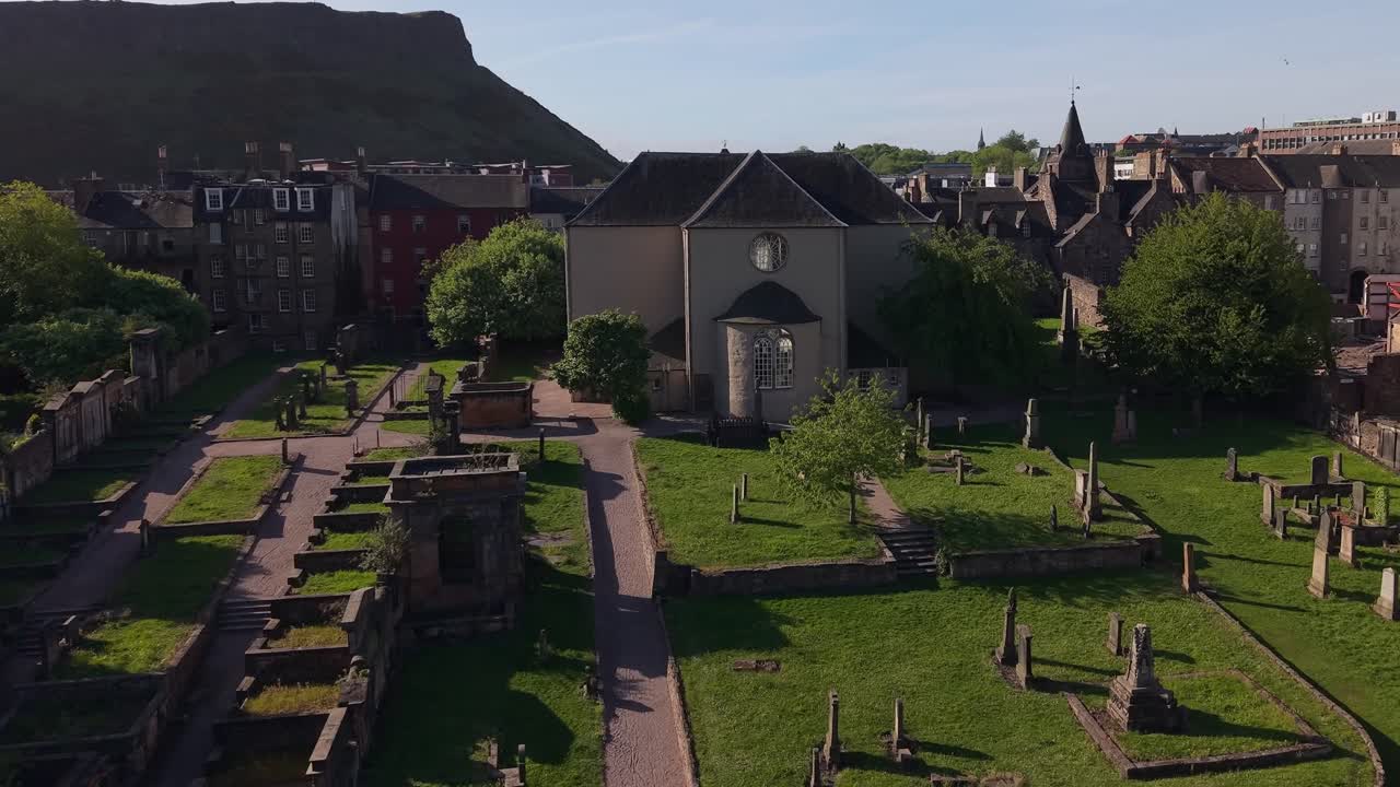 Smooth drone flight approaching Canongate Kirk, revealing its historic architecture and surrounding Edinburgh streets in a charming cityscape view