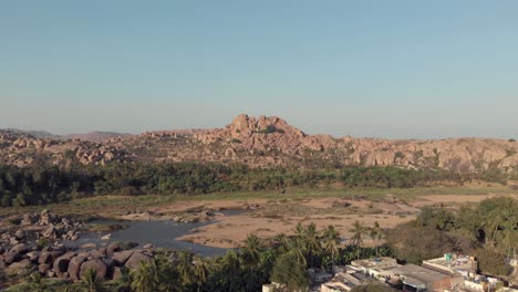 rocky landscape and barren tungabhadra riverbank at hampi town's edge, karnataka, india - aerial panoramic shot