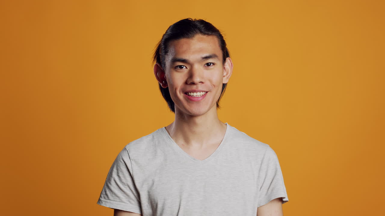 Cheerful smiling guy posing on orange background