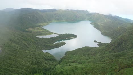 Breathtaking-aerial-view-of-Lagoa-do-Fogo's-pristine-waters-and-lush-green-surroundings