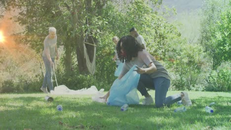 video of lights over diverse happy group picking up rubbish in countryside