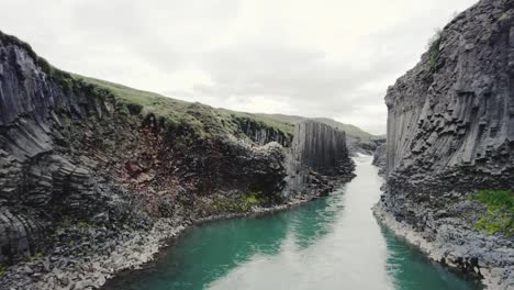 disparo de drones volando bajo a través del cañón studlagil en islandia 4k