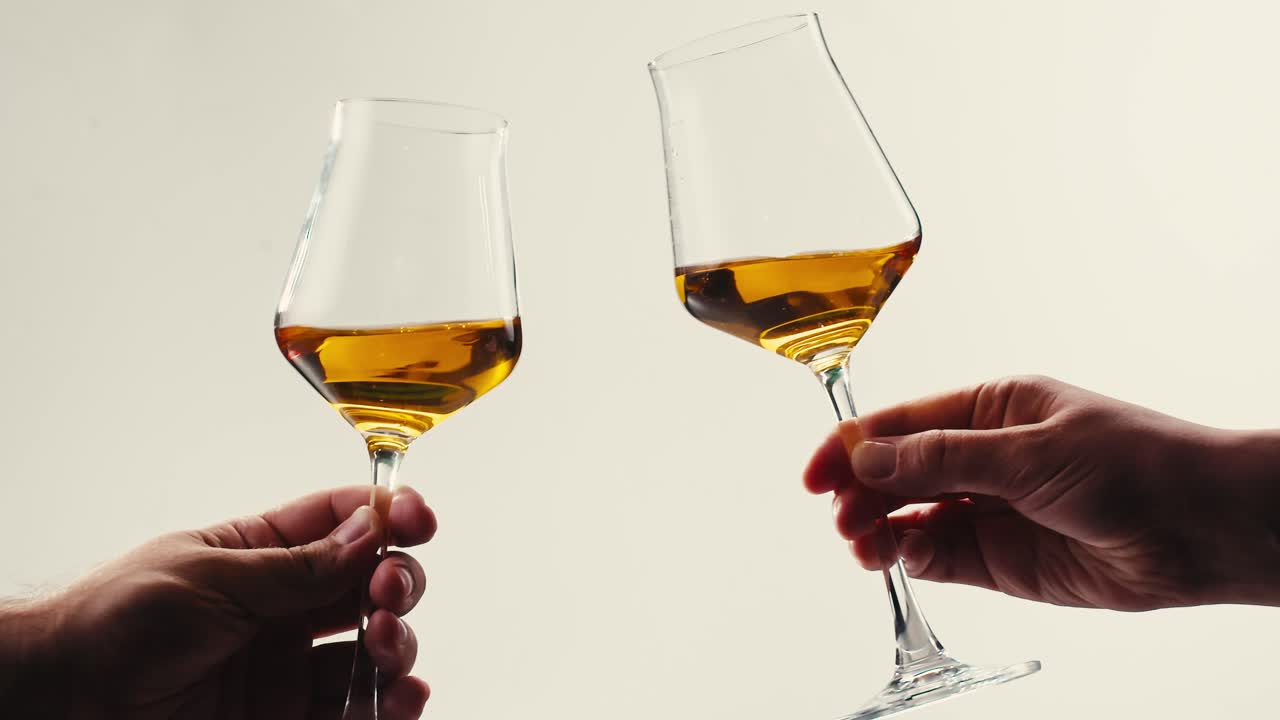 Orange or white wine bottle and glass against a sunset in a peaceful vineyard, pouring of ecological natural wine.