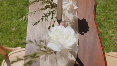 white roses in flower vases with candles in candleholders on wooden table in garden. outdoor wedding venue. overhead shot