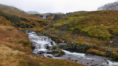 panoramic drone view of overcast skies, mountains, barren ground, valleys and waterfalls in iceland kirkjufell mountain near grundarfjordour