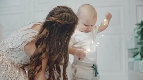 cute baby boy playing garland in living room. pretty sister caring small brother
