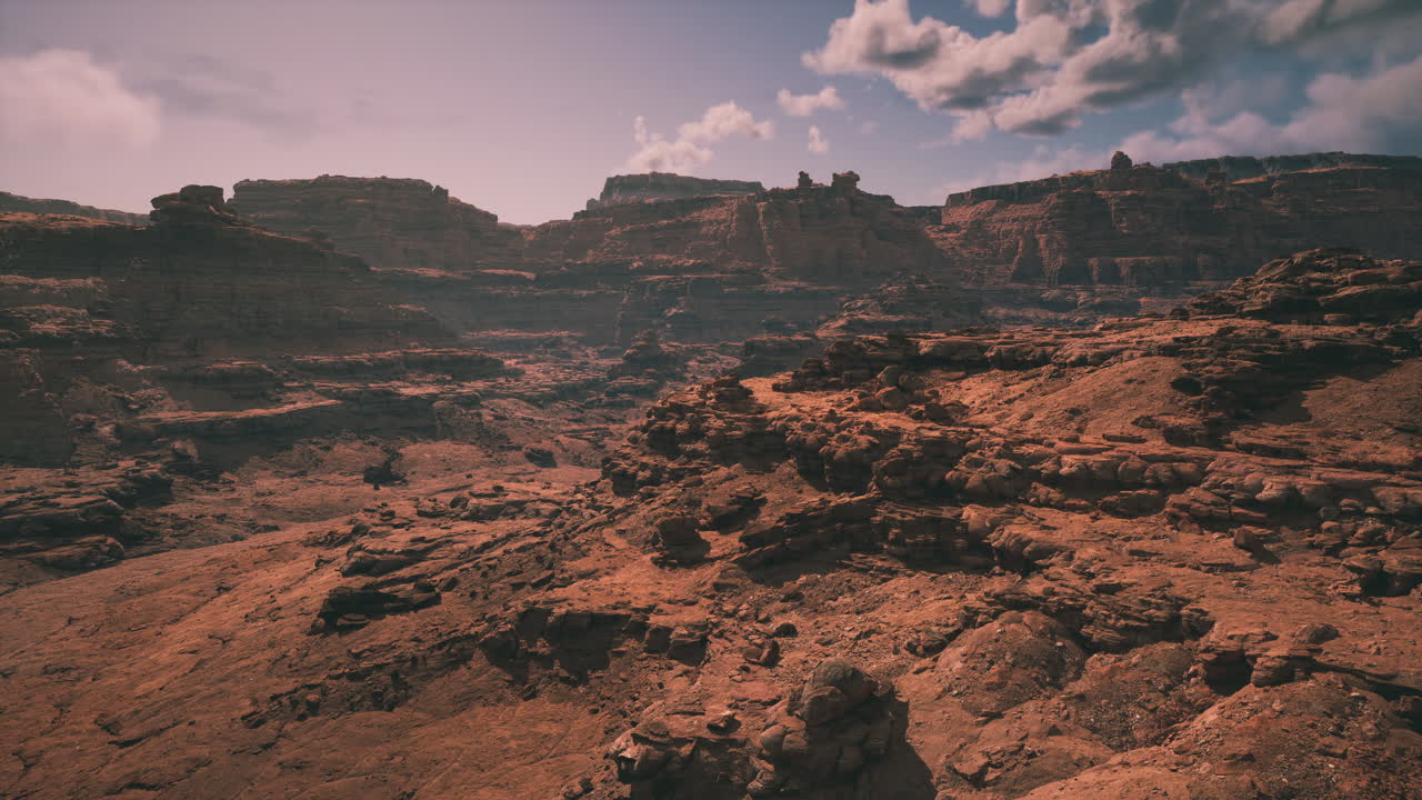 Vast arid landscape with rugged cliffs and clouds in the clear blue sky