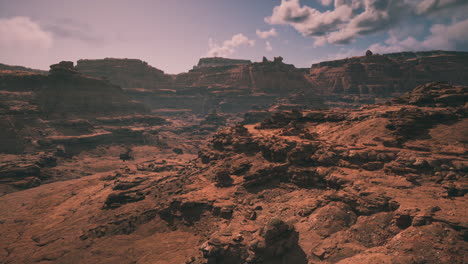 vast arid landscape with rugged cliffs and clouds in the clear blue sky