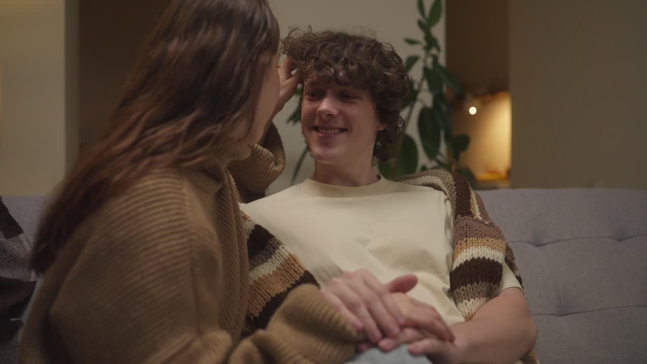 Affectionate couple holding hands on couch