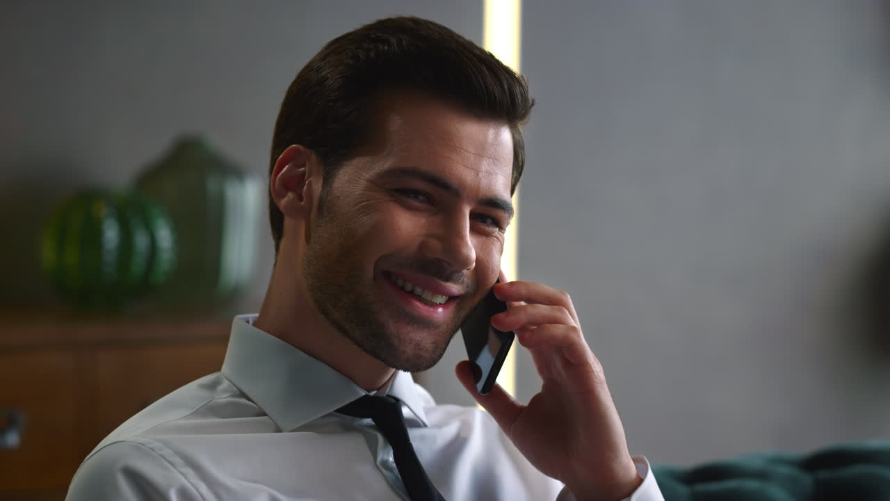 Portrait of happy businessman talking on mobile phone at remote workplace