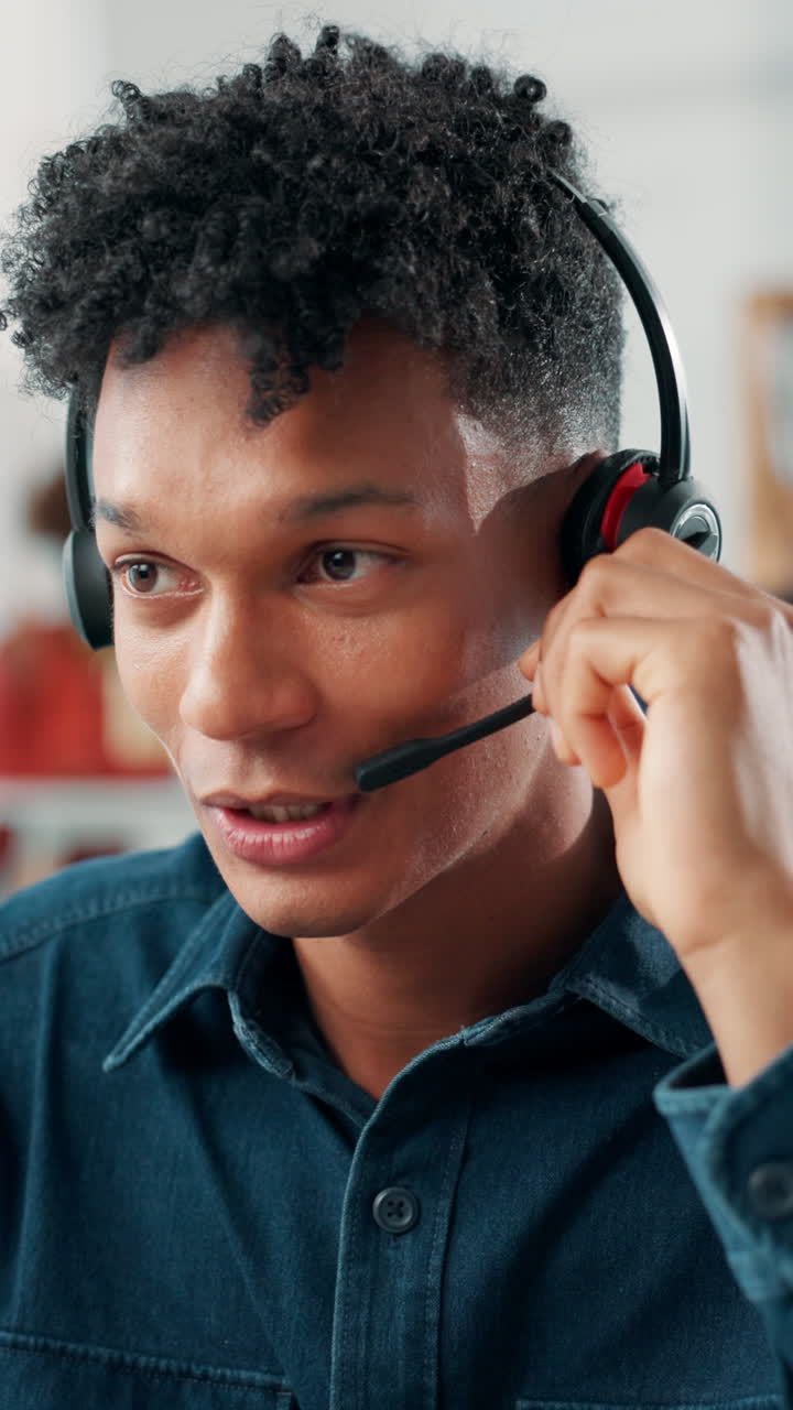 Giovane uomo con cuffie che parla e sorride in ufficio