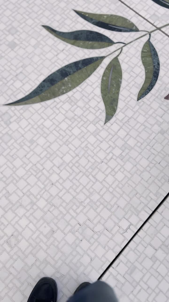 Person går på udsmykket mosaikflisegulv med blomstermønster