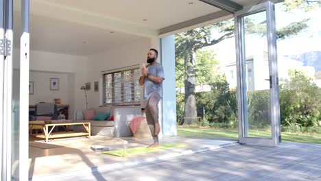 focused african american man practicing yoga using laptop at sunny home, slow motion