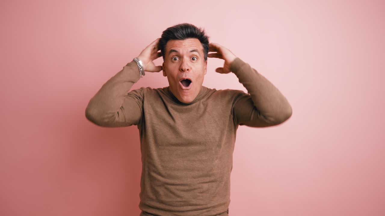 Surprised Man Reacts with Amazement and Excitement on Pink Background