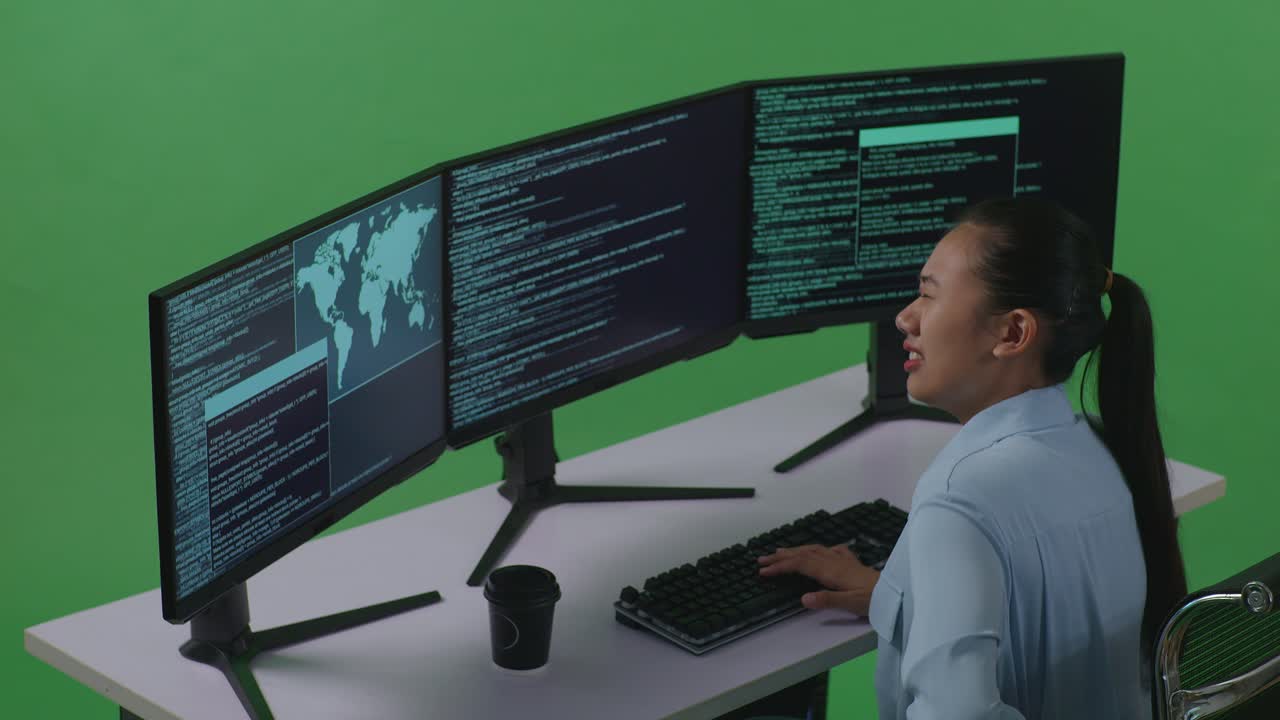 Side View Of Asian Woman Developer Having Backache While Write Code With Multiple Computer Screens In Green Screen Studio