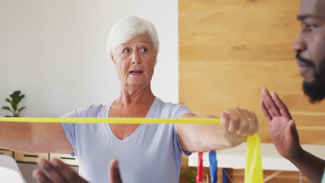 video of african american male physiotherapist exercising with caucasian senior woman