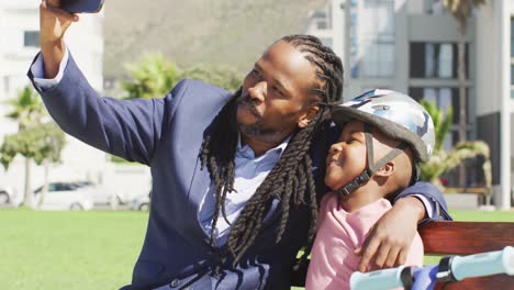 Video-Eines-Glücklichen-Afroamerikanischen-Vaters-Und-Sohnes-Im-Helm,-Die-Draußen-Ein-Selfie-Machen