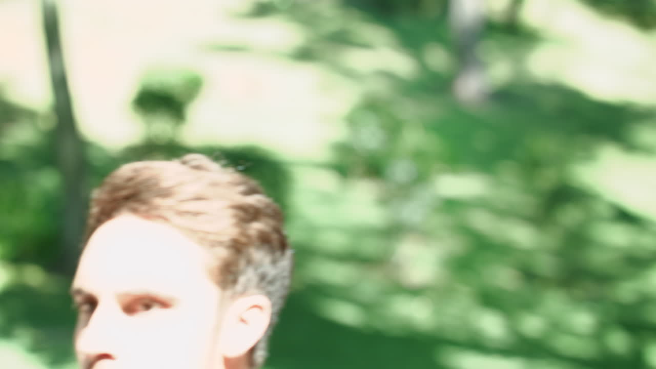 스포츠 남자가 휴대전화를 보고 여름 공원에서 달리고 있습니다.