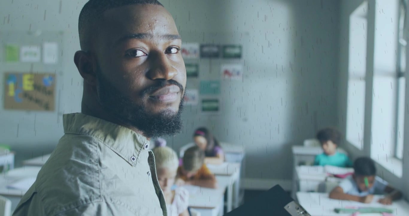 Insegnante maschio afroamericano che guarda la telecamera in classe.