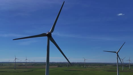 Wind-turbines-spin-in-a-vast-green-field-under-a-clear-blue-sky