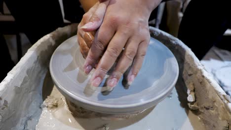 overhead close view of an african american hands spinning clay very sporadically while pushing the mold from above