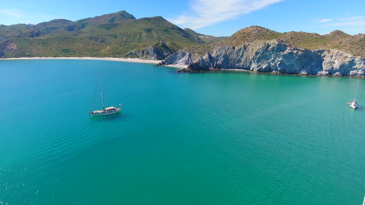 작은 산악 섬들의 바닥에 있는 순수한 해변을 따라 화려한 푸른색의 만에 정박한 모노 세일링 요트 그룹