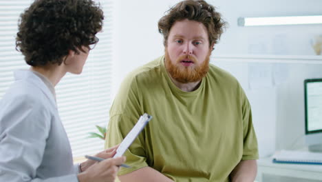 female dietician consulting with male patient in clinic