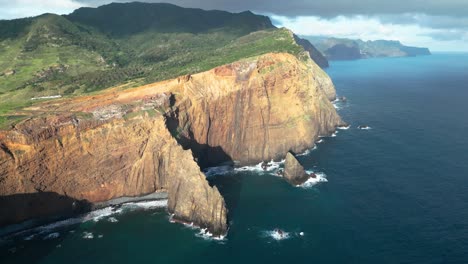 a sea cliff on the side of an island with waves hitting the shore