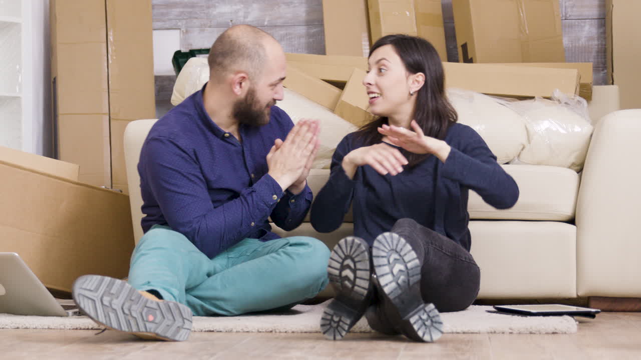 Pareja haciendo planes en su nuevo hogar rodeada de cajas de mudanza